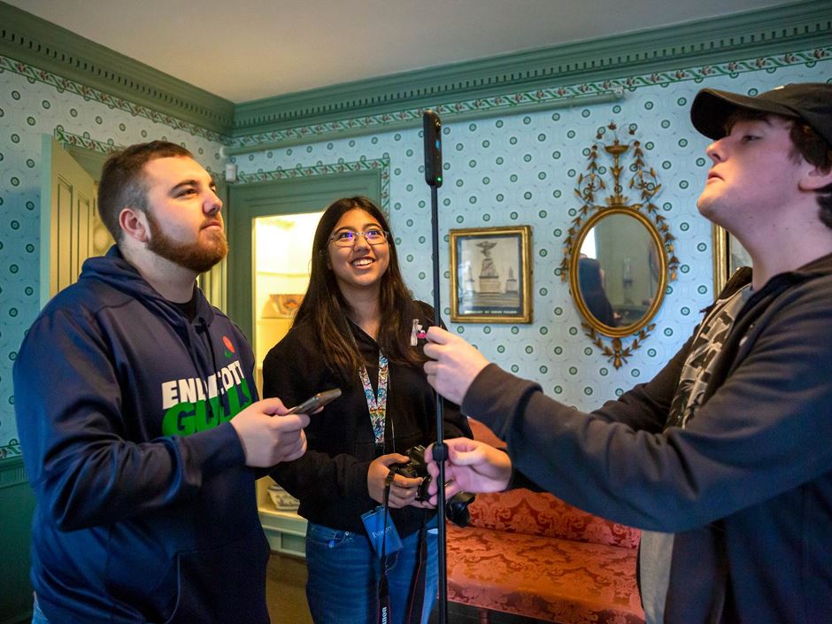 Three students standing in a historic home with a 360 camera.