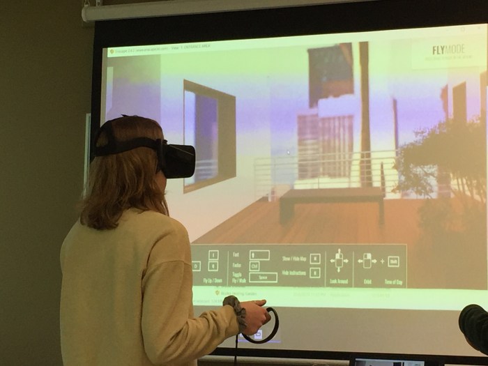 Interior Architecture student wearing a VR headset with hand controls explores a design project in the Oculus VR headset.